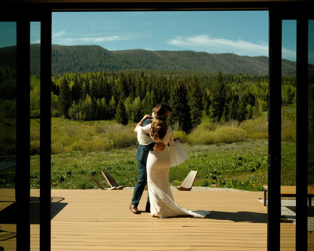 Erin and josh dancing together on the porch in the sun overlooking the mountains