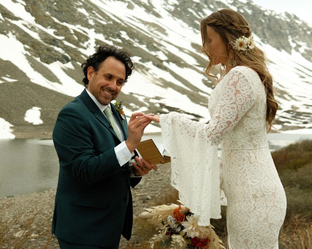 Josh putting erins wedding ring on with mountains in the background