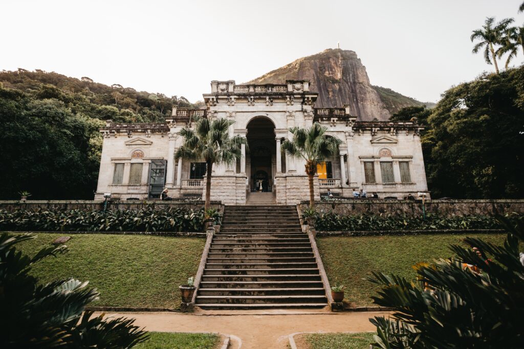 a view of the Parque Lage, a historical mansion surrounded by lush forest in Brazil