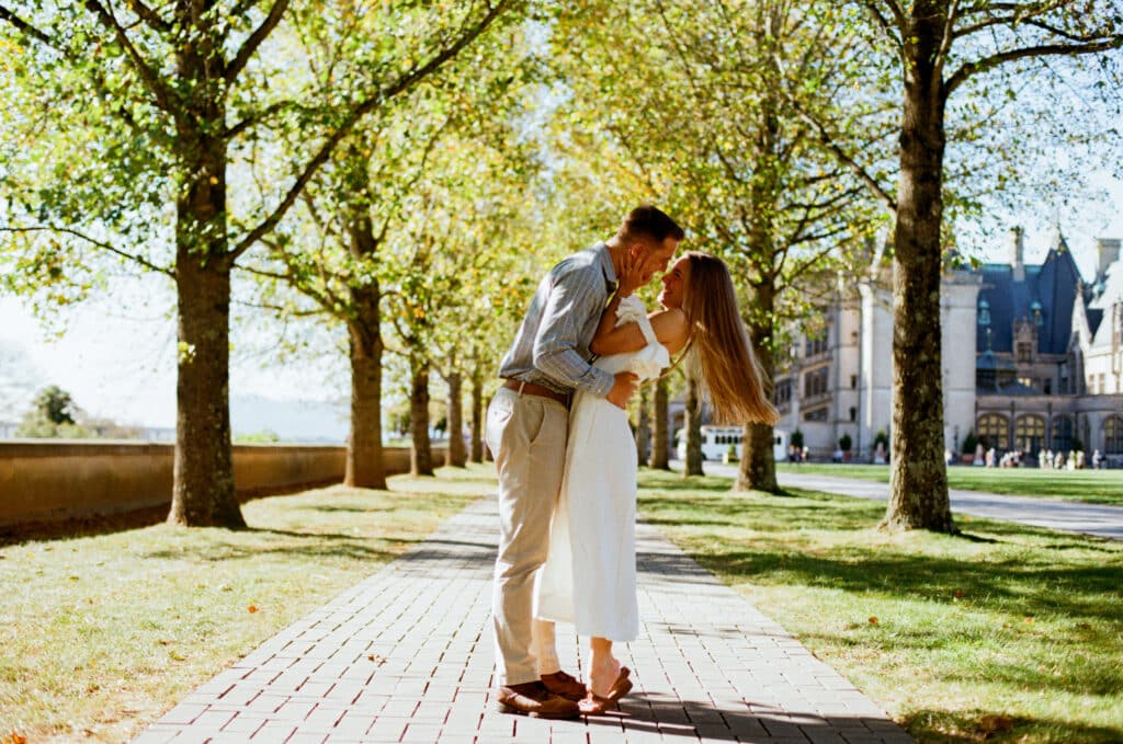 young couple kissing after getting engaged at the Biltmore estate in the fall in western North Carolina on film